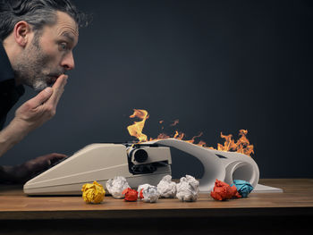 Man looking at burning typewriter against wall