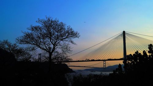 Silhouette of suspension bridge against sky during sunset