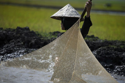 Close-up of man holding umbrella on field