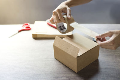 Close-up of human hand holding paper on table