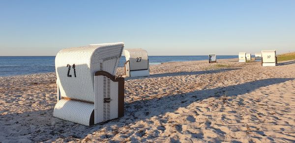 Hooded chairs on beach against clear sky