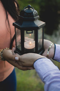 Close-up of man and woman hand holding lantern with illuminated candle