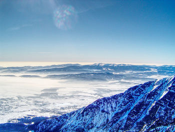 Scenic view of sea and mountains against blue sky