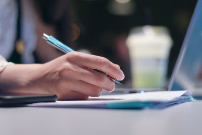 Midsection of woman using mobile phone on table