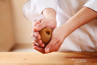 Midsection of woman preparing sweet baking food with dough at kitchen counter