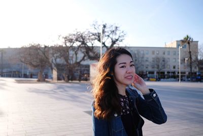 Portrait of beautiful young woman standing in city