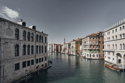 Canal passing through buildings against sky