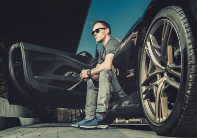 Full length of man looking away while sitting in car