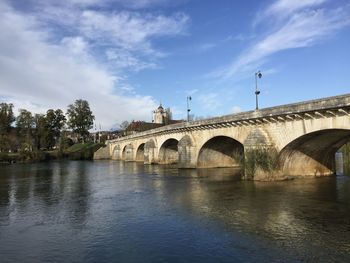 Arch bridge over river against sky