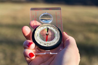 Cropped hand of woman holding navigational compass outdoors