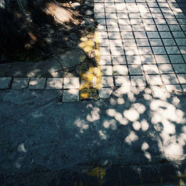 street, high angle view, sidewalk, cobblestone, puddle, paving stone, footpath, shadow, sunlight, asphalt, wet, outdoors, road, day, no people, reflection, pavement, wall - building feature, season, pattern