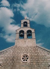 Low angle view of cross on building against sky