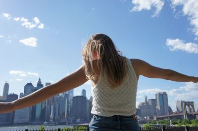 Rear view of woman standing by cityscape against sky