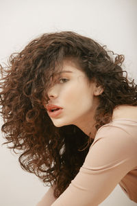 Serious female with curly hair looking at camera on white background in studio