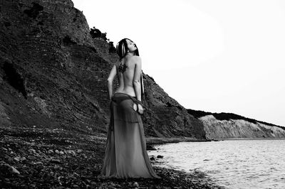 Woman standing on rock against clear sky