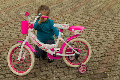 Full length of girl with bicycle standing against pink wall