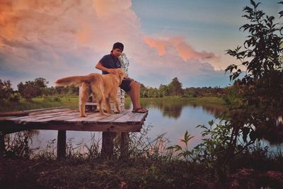 Man with dog standing in lake against sky