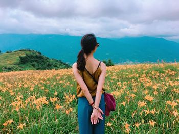 Young woman looking at camera on field against sky