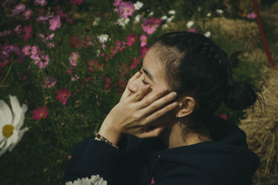 Close-up of woman with head in hand sitting amidst flowering plant