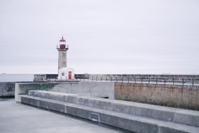 Lighthouse by building against sky