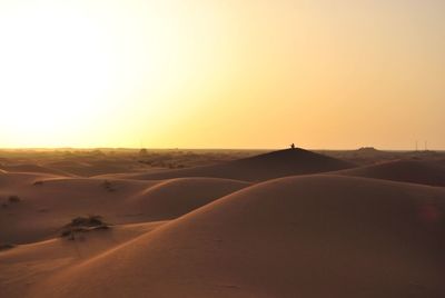 Scenic view of desert against clear sky during sunset