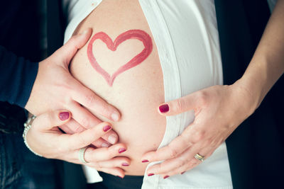 Close-up of couple's hands holding pregnant belly