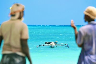 Rear view of man in sea against clear blue sky