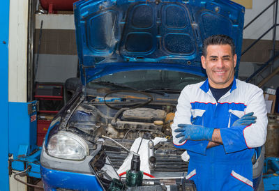 Portrait of smiling mechanic repairing car at auto repair shop