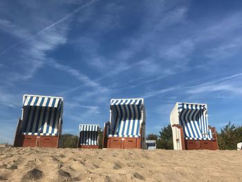Low angle view of hooded beach chairs against sky