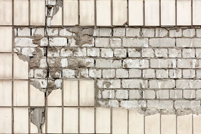 A fragment of the destruction of the facade of a wall with a fallen off rectangular facade tile.