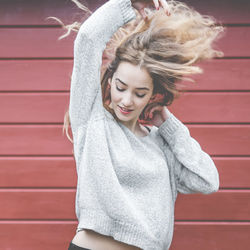 Beautiful woman tossing hair against wooden plank