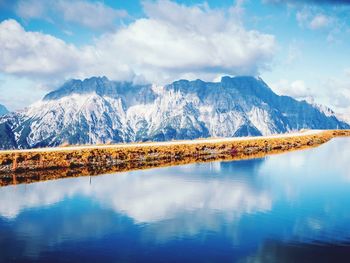 Scenic view of lake by snowcapped mountains against sky