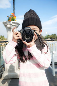 Man photographing through camera against sky