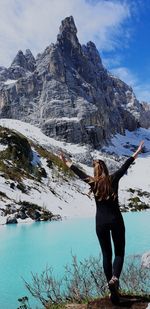 Full length of woman standing on snowcapped mountain against sky