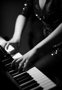 Arms, hands and upper body of young pianist wearing glittery top and playing lively music