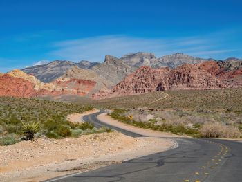 Road by mountains against blue sky