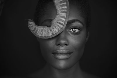 Close-up portrait of smiling young woman against black background