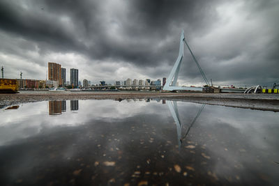 Reflection of city in water against cloudy sky