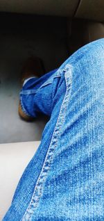 Low section of person sitting against blue wall