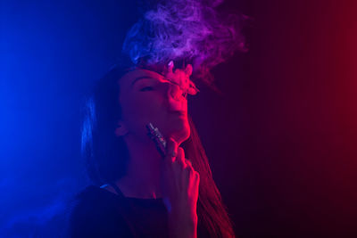 Portrait of man smoking cigarette against black background