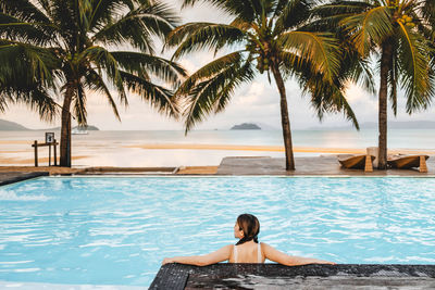 Full length of young man relaxing at swimming pool