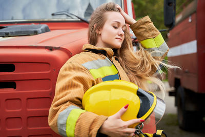 Female firefighter standing by truck