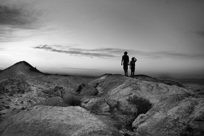 Rear view of men walking on landscape against sky