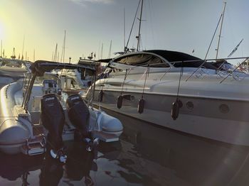 Sailboats moored on harbor against sky