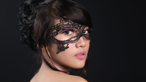 Portrait of beautiful woman wearing mask against black background