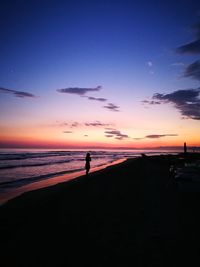 Silhouette person standing on beach against sky during sunset