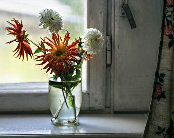 Defocused autumn flowers in a glass vase on windowsill. selective focus. close up