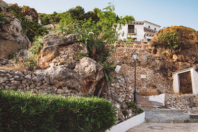 Plants and rocks by house against sky