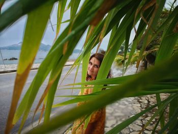 Portrait of young woman looking through plants