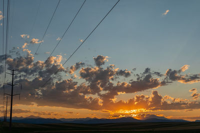 Low angle view of silhouette power lines against sky during sunset